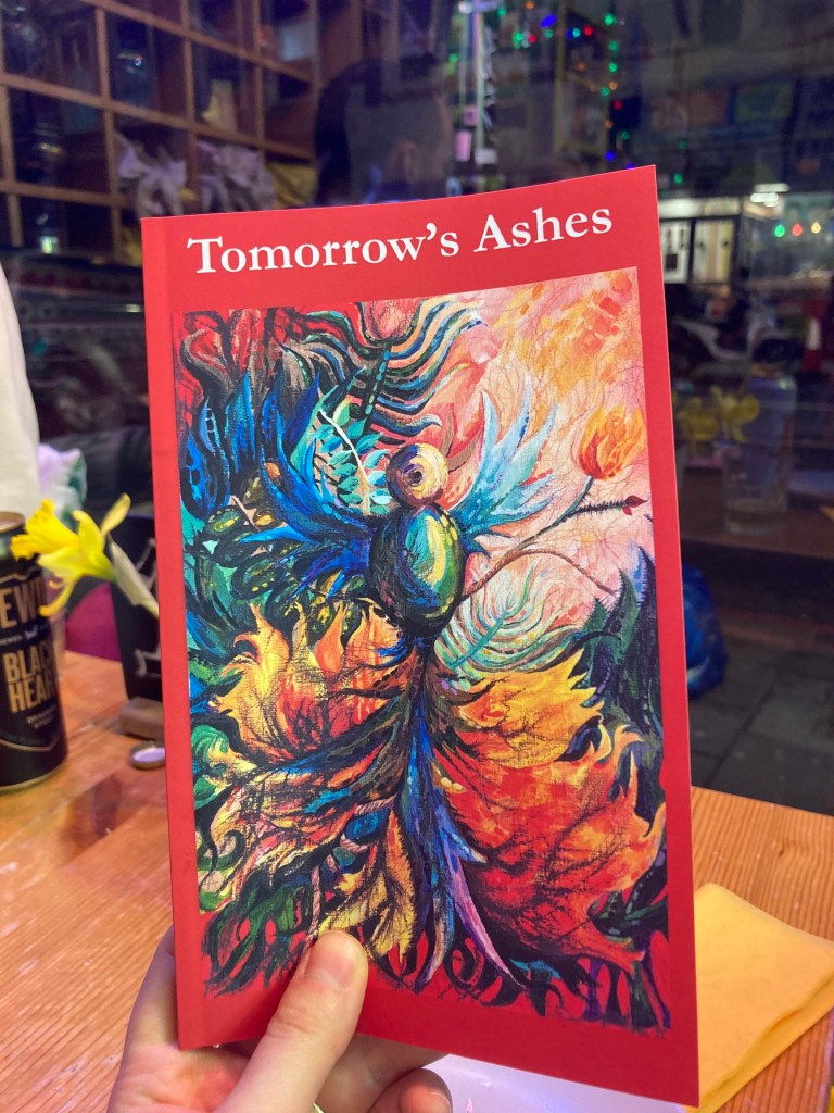 Image of a hand holding a copy of the book, Tomorrow's Ashes